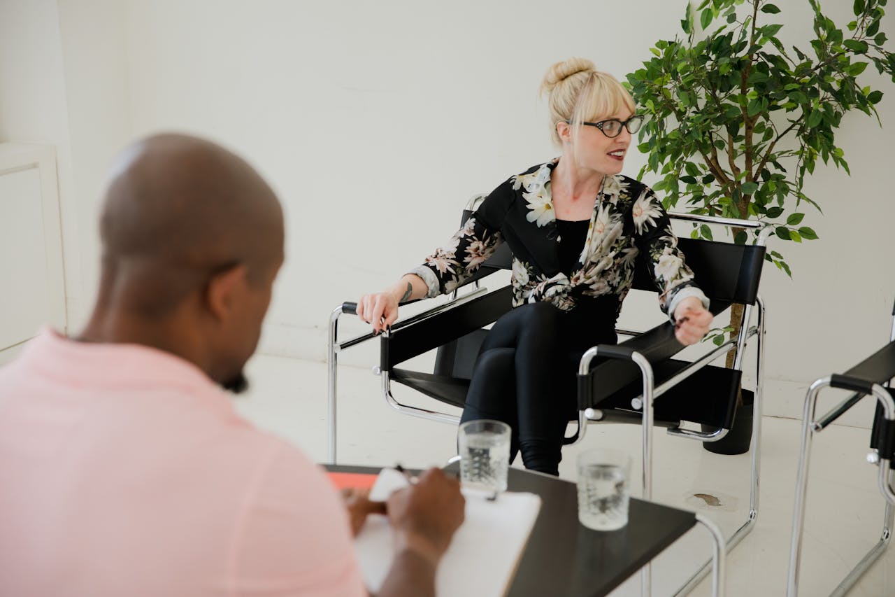 A therapy session with a diverse client and therapist discussing mental health.